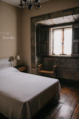 a bedroom with a bed and a window and a chair at Palacio Conde Toreno in Malleza