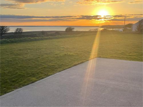 a road leading to a field with the sunset in the background at Ardmores Contemporary Beach House in Sluggera Cross Roads