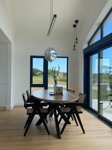 a dining room with a wooden table and chairs at Ardmores Contemporary Beach House in Sluggera Cross Roads