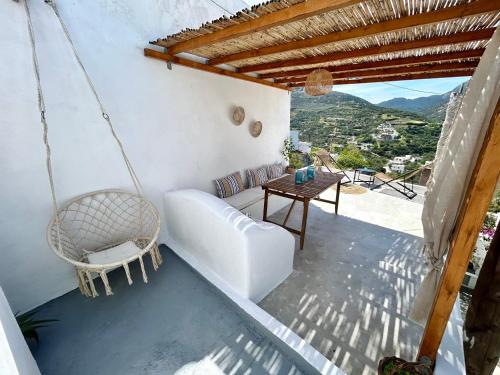 a porch with a swinging couch and a table at Babatseratsi skyrian studio 1 in Skiros