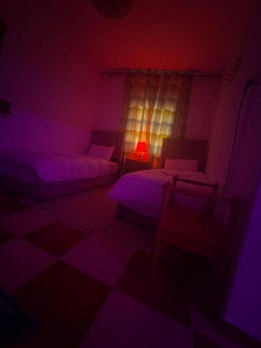a dark room with two beds and a lamp at Bleu home in Chefchaouene