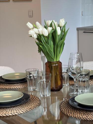 a vase of white tulips sitting on a table at Studio 77 - nowoczesny apartament w Otwocku in Otwock