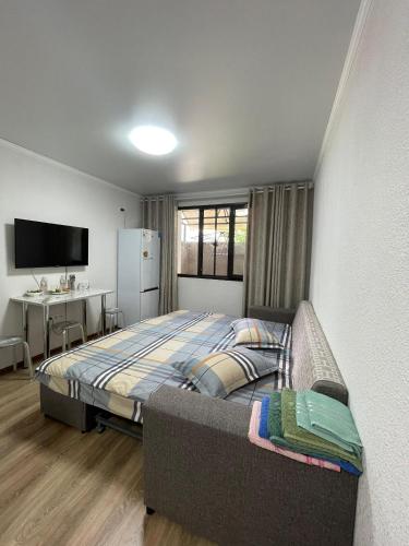 a bedroom with a bed and a desk and a television at Квартира на Иссык-куле в ЦО Радуга in Chon-Sary-Oy