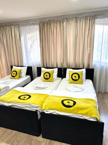 two beds in a bedroom with yellow and black pillows at Aura Plaza Hotel in Tbilisi City
