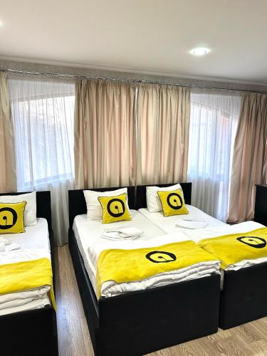 two beds in a room with yellow and black pillows at Aura Plaza Hotel in Tbilisi City