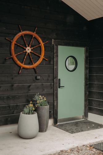a wooden wall with a door and a ship wheel at Hällesdalens Gård - semesterhus i Bohuslän in Svenshögen