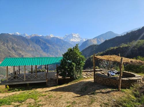 Un edificio con techo verde con montañas al fondo. en Chaukhamba Cradle, en Ukhimath