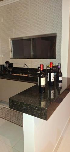 two bottles of wine sitting on a counter in a kitchen at Casa completa com área gourmet e piscina -2 quartos in Macapá