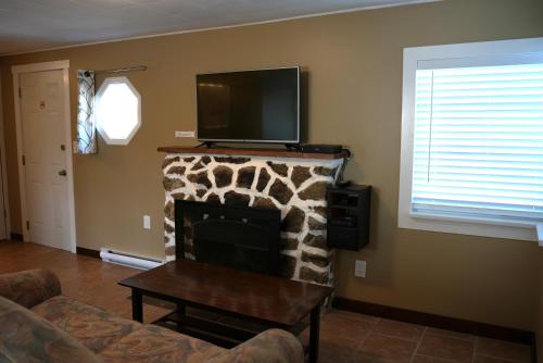 a living room with a fireplace with a tv on top at Malahat Bungalows Motel in Malahat