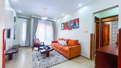 a living room with an orange couch and a table at The Cozy Nest in Kampala