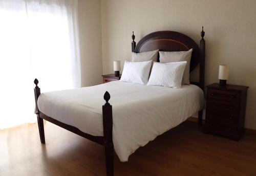 a bedroom with a large bed with white sheets and pillows at Delfim Beach House in Quiaios