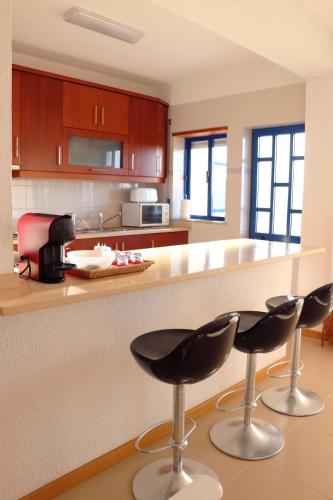 a kitchen with two bar stools in front of a counter at Delfim Beach House in Quiaios