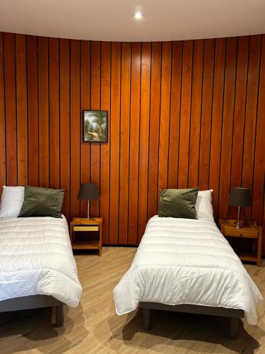 deux lits dans une chambre aux murs en bois dans l'établissement Montciel Jura, à Lons-le-Saunier