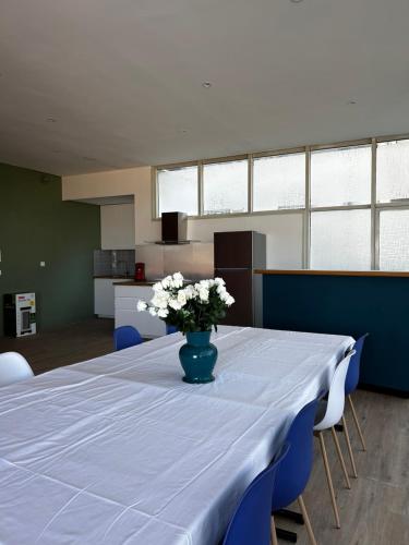 une table avec un vase bleu et des fleurs blanches sur elle dans l'établissement Montciel Jura, à Lons-le-Saunier