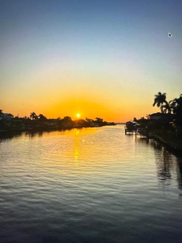 a sunset over a body of water with palm trees at Cape Coral Paradise - Spectacular View in Cape Coral
