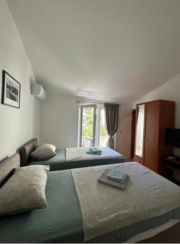 two beds in a room with a window at Apartments Manojlovic in Budva