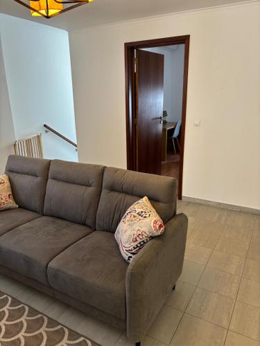 a brown couch with two pillows sitting in a living room at Casa Cruzeiro AL - by the sea OCEANTUR in Rosário-Lagoa