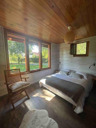 une chambre avec un lit, une chaise et des fenêtres dans l'établissement La Demeure des Fougères, à Gastes