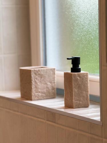 une salle de bain avec deux distributeurs de savon et une fenêtre dans l'établissement Casa Escuela, à Plougastel-Daoulas