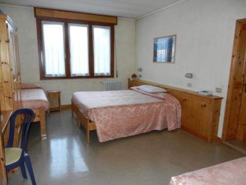 a bedroom with two beds and a table and chairs at Albergo Adele in Bormio