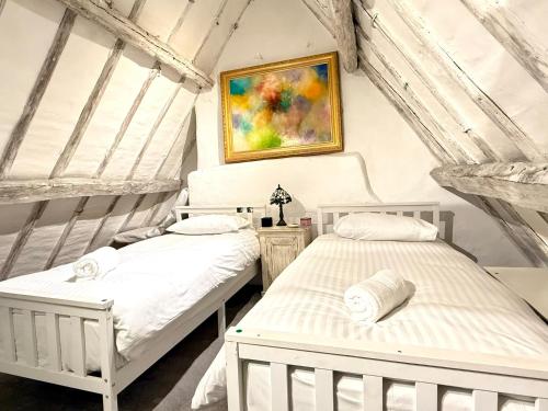 two white beds in a room with a painting at Swan Cottage, 5-Bedroom, Canal View, River, Private gardens, Free Parking's, WiFi, Oxford in Kidlington