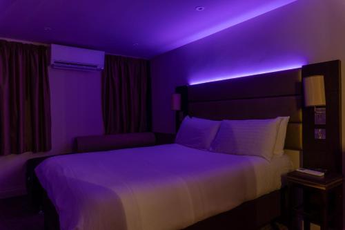 a bedroom with a bed with a purple lighting at SHARNBROOK INN Hotel Restaurant Bar Perfect For Santa Pod in Bedford