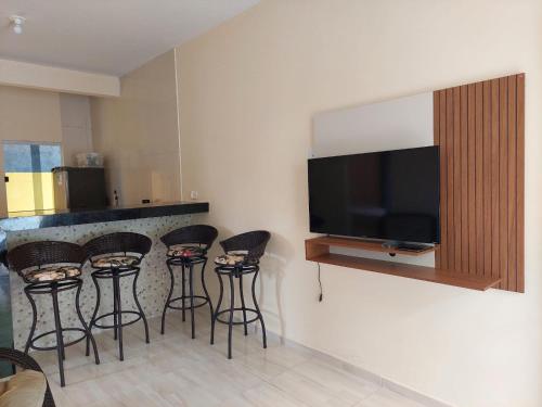 a kitchen with a bar with stools and a flat screen tv at Aconchego da Zuca in Marau