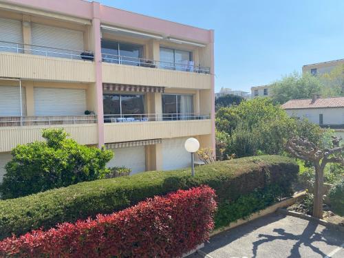 un bâtiment avec des buissons et des fleurs devant lui dans l'établissement Appartement Fréjus - T3 - 2 chambres - 5 personnes - garage - clim - port à 300 m, à Fréjus