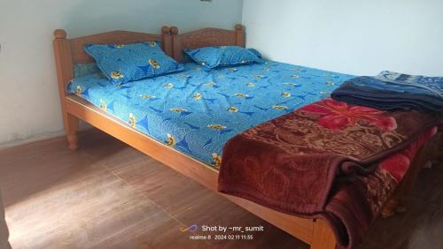 a bed with a blue comforter and pillows on it at Hari Har guest house in Chhatarpur