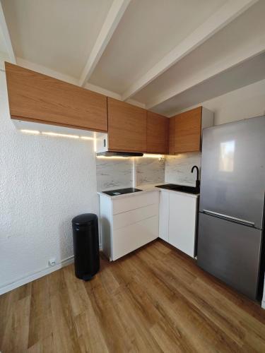 une cuisine avec des armoires blanches et un réfrigérateur en acier inoxydable dans l'établissement L'abri-côtier, au Cap d'Agde