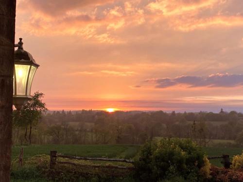 un coucher de soleil sur un champ avec un pôle lumineux dans l'établissement Gite Le Coucher du Soleil - 30mins Puy du Fou, à Saint-André-sur-Sèvre