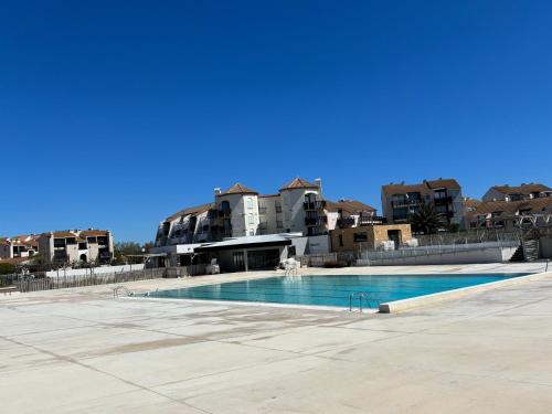 une grande piscine avec des bâtiments en arrière-plan dans l'établissement Cozy apartment in Cap Coudalère, lake and pool view, 4 people, au Barcarès