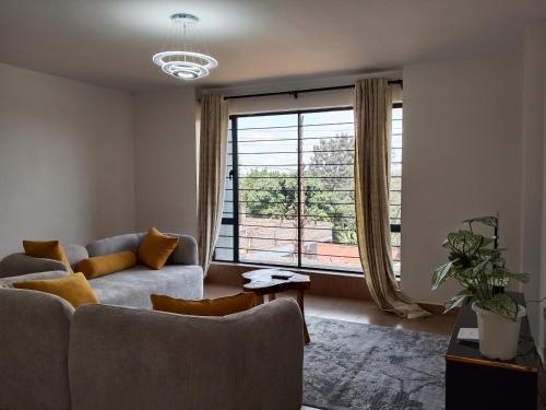 a living room with a couch and a large window at Cozy Serene Two Master Bedroom in Nairobi