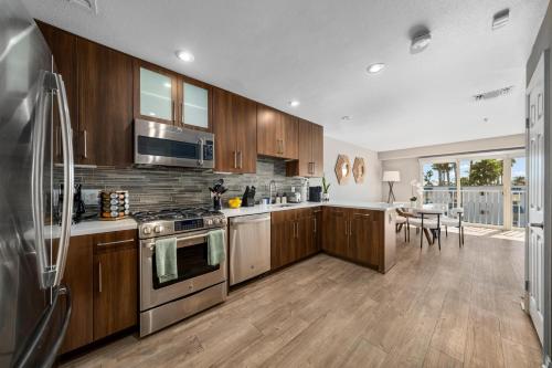 a kitchen with wooden cabinets and stainless steel appliances at Ocean Views - Rooftop Pool 2BR Santa Monica in Los Angeles