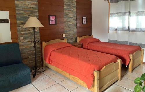 a bedroom with two beds with red sheets and a chair at Casa Color in Florida