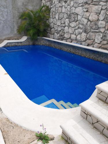 a swimming pool in front of a stone wall at Tziimin Nahil Cozumel in Cozumel