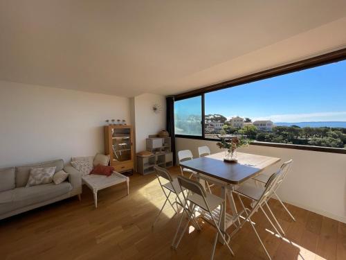- un salon avec une table, des chaises et une grande fenêtre dans l'établissement Bormes les Mimosas au coeur du village historique, à Bormes-les-Mimosas