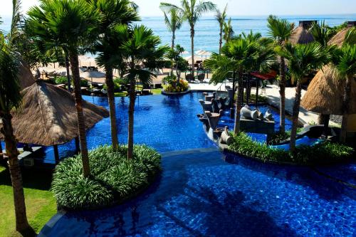 ヌサドゥアにあるHoliday Inn Resort Bali Nusa Dua, an IHG Hotel - CHSE Certifiedのヤシの木と海を望むリゾートスイミングプール