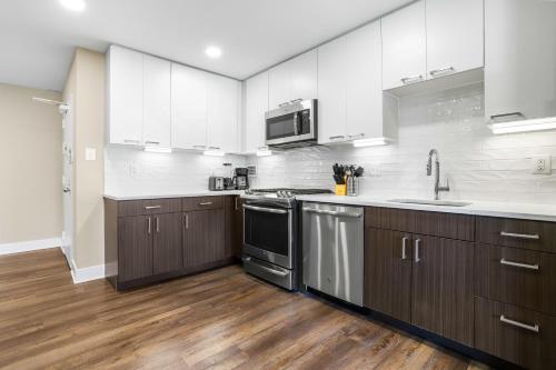アーリントンにあるCrystal City Escape Stylish Apt Close to DC Airportのウッドフロアのキッチン(白いキャビネット付)