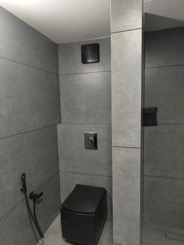 a bathroom with a toilet with a black stool at Maleyam Homestay Riverside in Kozhikode