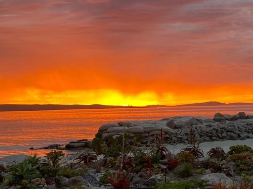 a sunset over the water with rocks in the foreground at Carpe Diem in Langebaan