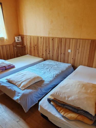 two beds in a room with wooden walls at Domaine la butte de Lauray in Moncontour-de-Poitou