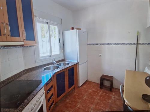 a kitchen with a sink and a white refrigerator at Duplex Barbados Aguamarga in Agua Amarga