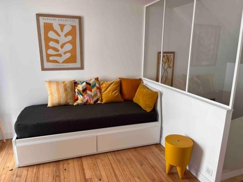 a couch with pillows on it in a room at PETITE MAISON à 100M DE LA MER ET DU CENTRE VILLE in Concarneau