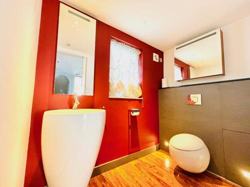 a bathroom with a toilet and a red wall at Elegant and Modern 3-Bedroom Victorian House in Westminster, London in London