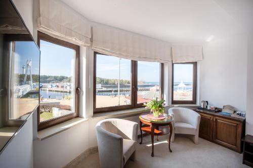 a living room with a table and chairs and windows at COLUMBUS Apartamenty Ustka - Limanowskiego 1 in Ustka