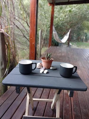 two coffee cups sitting on a table on a deck at Tu lugar de relax a 2 cuadras de la playa Se reserva con seña in Guazuvira