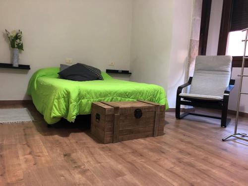 a bedroom with a bed with a green comforter and a chair at -Precioso apartamento en pleno corazón de A Guarda in A Guarda