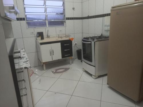a small kitchen with a stove and a refrigerator at Pousada do Bene - Aluguel Casa in Guarujá