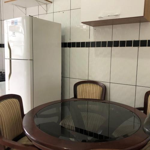 a kitchen with a glass table and chairs and a refrigerator at Pousada do Bene - Aluguel Casa in Guarujá